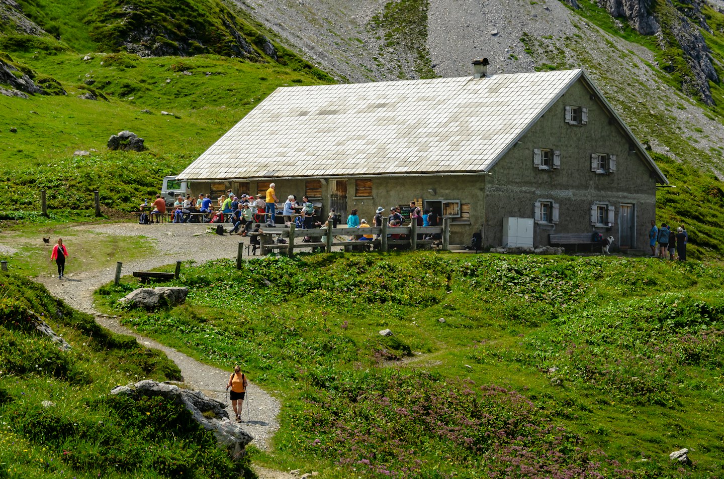 Menschen entspannen sich in einer Berghütte auf einer Bergwiese.